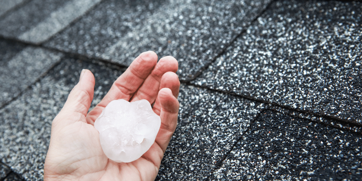 Preparing Your Home for Kentucky Storm Season - hand holding a large piece of hail on a rooftop